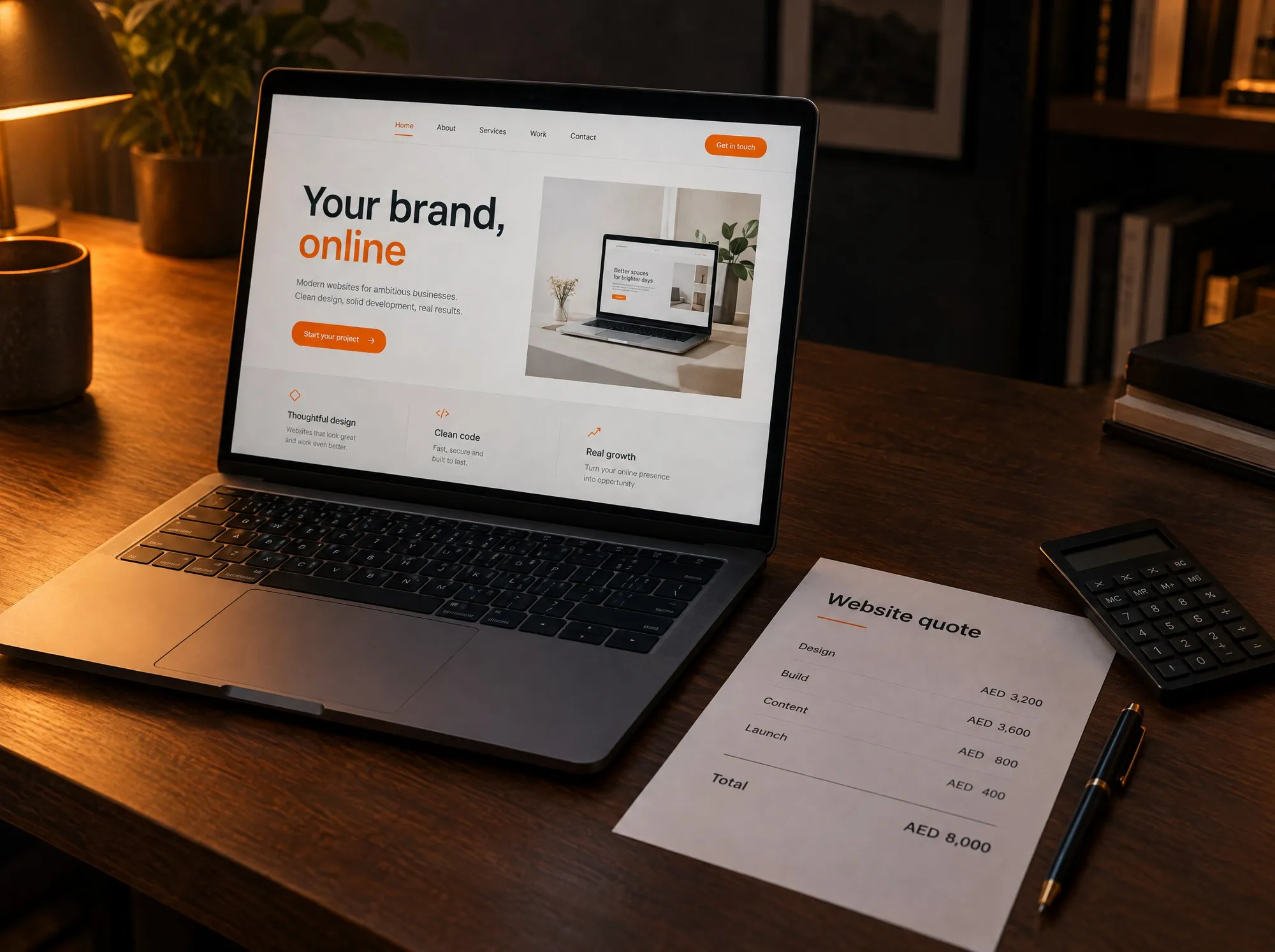A laptop showing a website design beside a printed website quote with line items in AED, a calculator and a pen